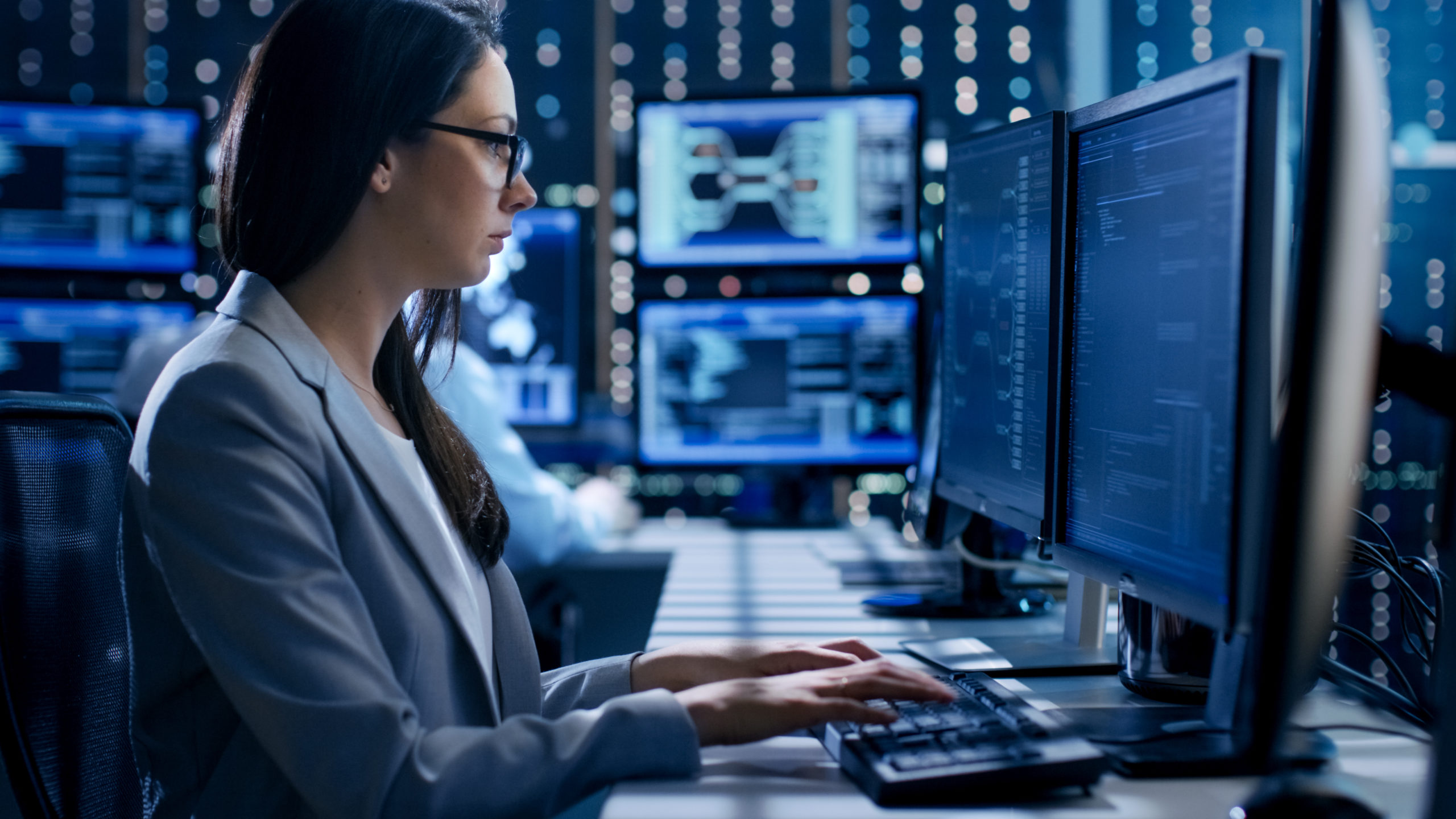 Woman sitting at desk in front of monitors
